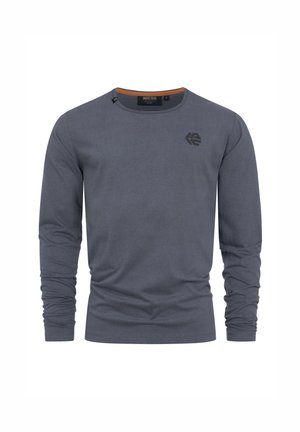 T-shirt à manches longues col rond gris ardoise avec un petit logo noir sur la poitrine gauche et une bordure orange à l'intérieur du col.