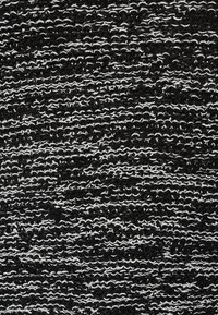 Teksturowana tkanina z wplecionym wzorem naprzemiennych czarnych i białych nici, tworząca efekt pasków o zróżnicowanej głębokości powierzchni.