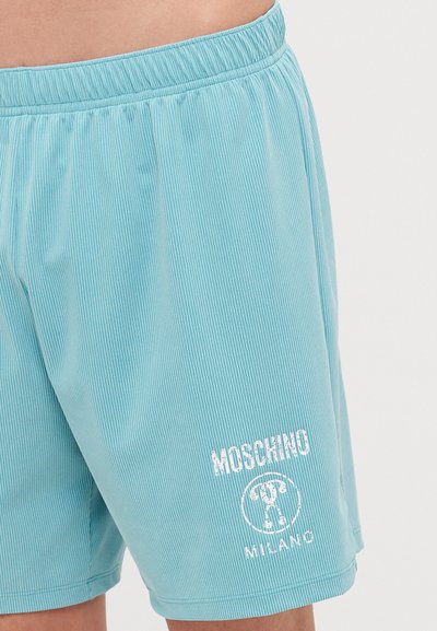 Svetlomodré plavky s vertikálnymi pruhmi, elastickým pásom a bielym logom s výrazným nápisom "Moschino Milano".