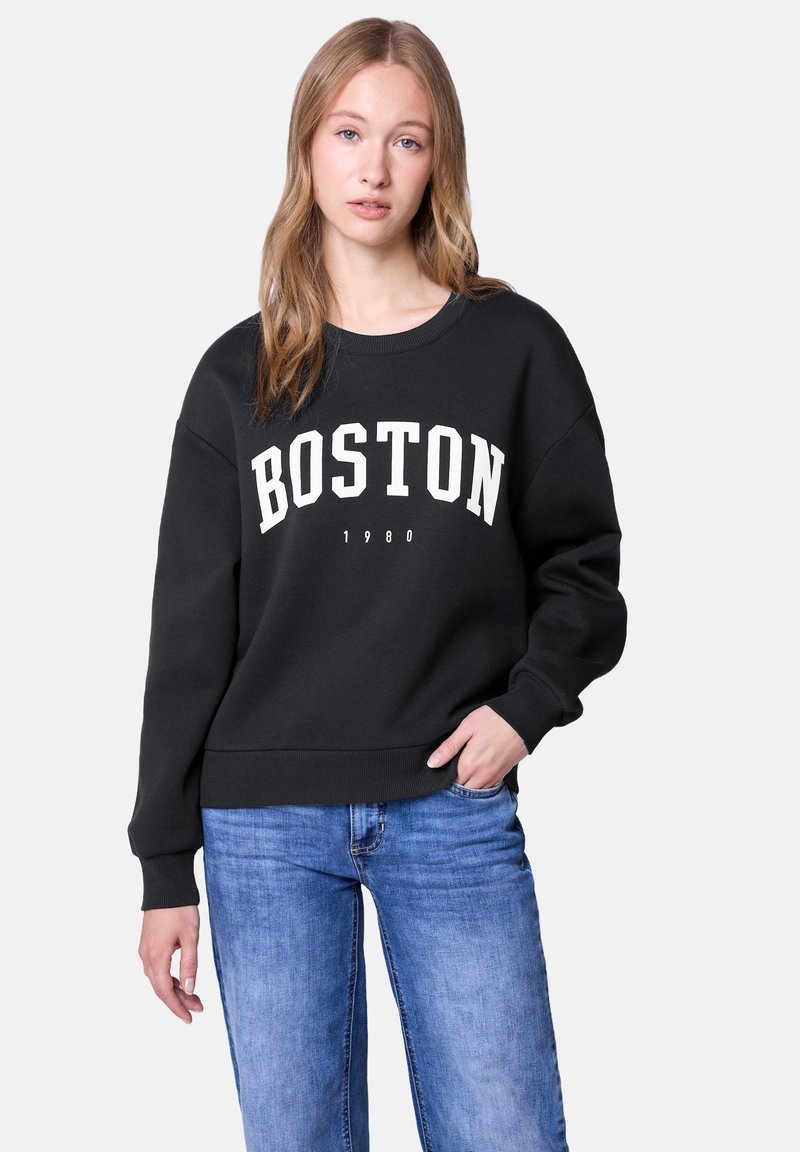 Czarny sweatshirt z nadrukiem "BOSTON 1980" w białym kolorze. Posiada okrągły dekolt, ściągacze na rękawach oraz luźny krój, zestawiony z niebieskimi dżinsami.