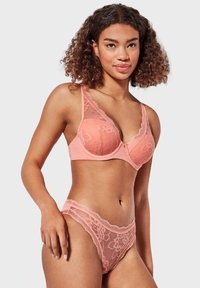 Reggiseno in pizzo pesca e perizoma abbinato con motivi floreali. Materiale in rete morbida, spalline regolabili e bordi in pizzo ondulato.