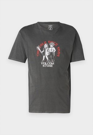 T-shirt gris foncé en coton avec une coupe décontractée. Présente un imprimé graphique de deux figures et le texte "Trouble Since 1991" en rouge.