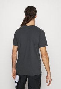 T-shirt à manches courtes gris foncé en coton. Doté d'un col rond et d'un design simple avec une texture lisse. Convient pour un usage décontracté.
