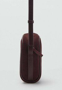 Sac en daim bordeaux avec une forme rectangulaire structurée, des accents en cuir lisse et une bandoulière amovible.