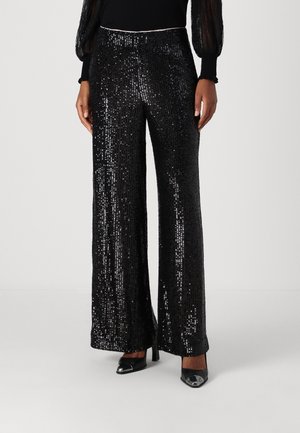 Schwarze Paillettenhose mit weitem Bein, glänzendem Finish und tailliertem Bund, kombiniert mit schwarzen High Heels.