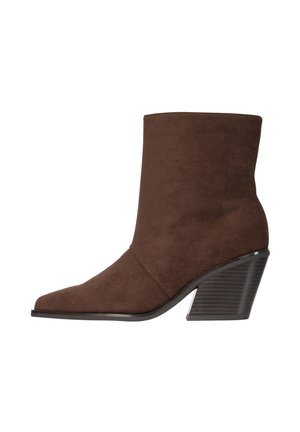 Bruine suède enkellaars met een puntige neus en een gestapelde blokhak, zijaanzicht op een witte achtergrond.