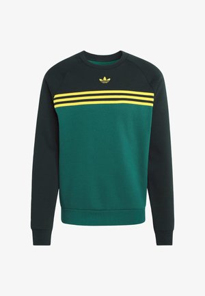 Žalias džemperis su tamsiai žalia liemeniu, geltonomis ir juodomis horizontaliomis juostomis per krūtinę, ribbintomis rankogaliais ir apvalia iškirpte.