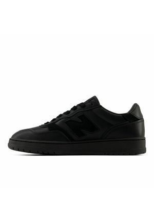 Sort lav top sneaker med polstret krave, snørelukning foran og tyk sål, vist fra ydersiden på en hvid baggrund.