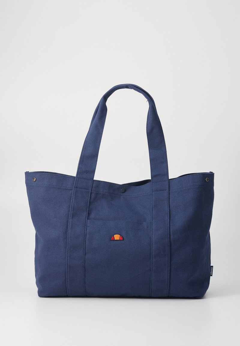 Grand sac fourre-tout en tissu bleu marine avec deux longues anses et un petit logo coloré en forme de demi-cercle sur la poche avant.