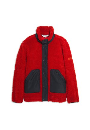 Veste en fourrure rouge avec un devant en nylon noir, dotée d'un col haut et de deux poches latérales zippées. Fini texturé avec une apparence douce.
