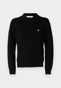 Maglione nero a maglia con colletto polo e maniche lunghe. Caratterizzato da una tasca sul petto con un'identità a pulsante. Texture morbida, design attillato.