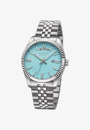 Montre en acier inoxydable avec un cadran bleu clair texturé. Présente une lunette striée, des marqueurs d'heure en argent et un guichet de date. Bracelet en métal.