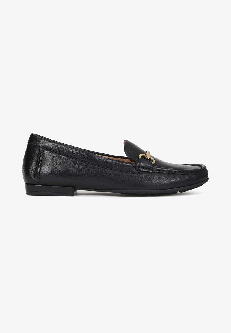 Mocassin noir en cuir sans lacets avec un petit talon et un détail en métal doré sur le dessus, vue de côté.