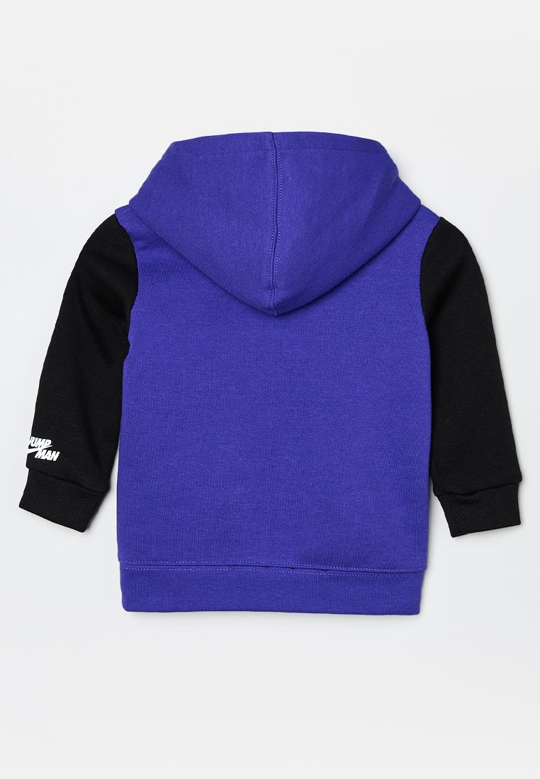 Sudadera morada con mangas negras, que cuenta con un bolsillo tipo canguro y puños acanalados. La parte posterior muestra un logo blanco en la manga izquierda.
