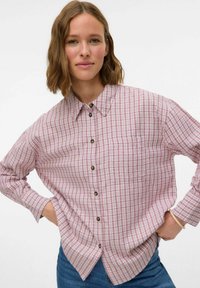 Roze en witte geblokte blouse met kraag, lange mouwen en een zak. Heeft een afgeronde zoom en bruine knopen.