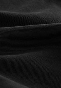 Zwarte stof met een gladde, licht getextureerde oppervlakte, met subtiele ribbels en plooien, een egale kleur en een zachte uitstraling.