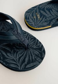 Infradito navy con una texture a foglia, realizzati in tessuto e gomma. Presentano una fascia tra le dita e un elegante logo dorato sulla suola.
