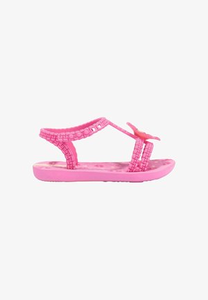 Sandalo rosa per bambini con cinturini intrecciati, motivi floreali sulla suola interna e decorazione a farfalla sul cinturino frontale.