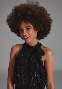 Czarny top na halter wykonany z cekinowej tkaniny, charakteryzujący się falbaną na dekolcie, gładką fakturą i błyszczącym wykończeniem.