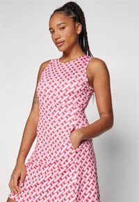 Sukienka bez rękawów z dopasowaną górą w różowo-białym geometrycznym wzorze, z bocznymi kieszeniami i gładką fakturą.
