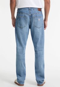 Heledad sinises teksad, lõdva lõikega, nähtavate õmblustega, kahe tagataskuga ja nahast plaastriga vöökohal. Õrnalt kulunud detailid.