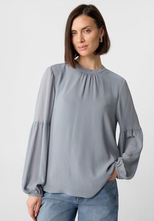 Hellgraue Bluse mit langen Ärmeln, plissiertem Ausschnitt, Ballonärmeln und elastischen Bündchen, aus einem glatten, fließenden Stoff gefertigt.