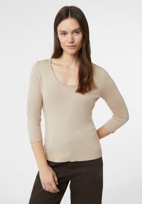 Beżowy sweter z dekoltem w łódkę i rękawami do połowy przedramienia, wykonany z miękkiego materiału. Krój dopasowany, z prążkowanymi akcentami na mankietach i dolnym brzegu.