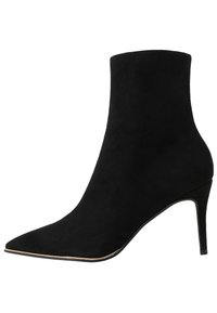 Bottine noire en daim avec un bout pointu, un talon haut fin et une silhouette élégante. Dotée d'une texture lisse et d'un bord de semelle orné d'un accent doré.