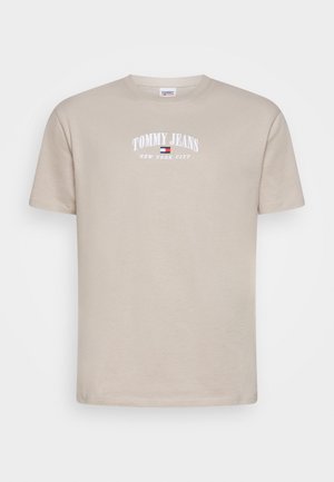 Beżowy t-shirt z krótkim rękawem i okrągłym dekoltem z nadrukiem "TOMMY JEANS" i "NEW YORK CITY" w kolorze białym nad małym logo w kolorach czerwonym, białym i niebieskim.