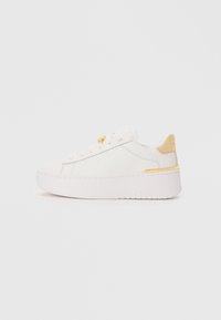 White sneaker with a smooth leather upper, contrasting yellow heel tab, thick white platform sole, and minimalistic lace-up design.