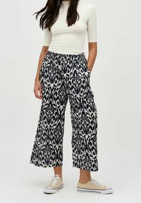 Culottbyxor i marinblå och vit ikat-mönster, med breda ben, elastisk midja och sidofickor, kombinerade med sneakers.