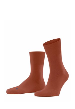 Baumwollmischungssocken in verbranntem Orange mit geripptem Bund. Der knöchelhohe Schnitt hat eine glatte Textur und eine subtile blaue Akzentuierung in der Nähe der Zehen.