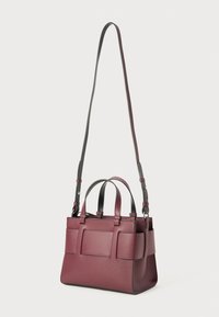 Sac à main en cuir bordeaux avec une forme structurée, deux poignées supérieures et une bandoulière grise amovible. L'avant présente deux accents similaires à des poches.