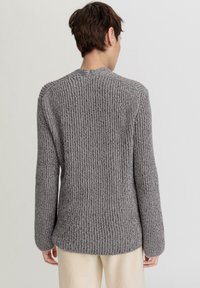 Grauer, gerippter Strickpullover mit hohem Kragen und langen Ärmeln, der über eine weiche Textur und einen lässigen Schnitt verfügt.