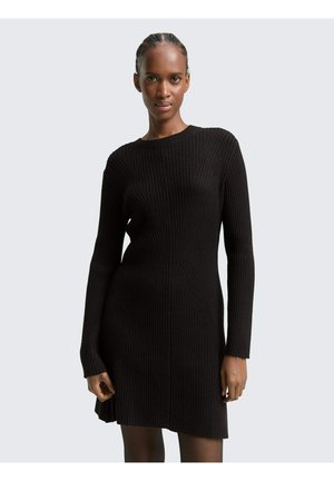 Robe en tricot côtelé noir avec des manches longues, un col rond et un motif texturé. Le design mi-long met en valeur des lignes structurées et une légère évasement.