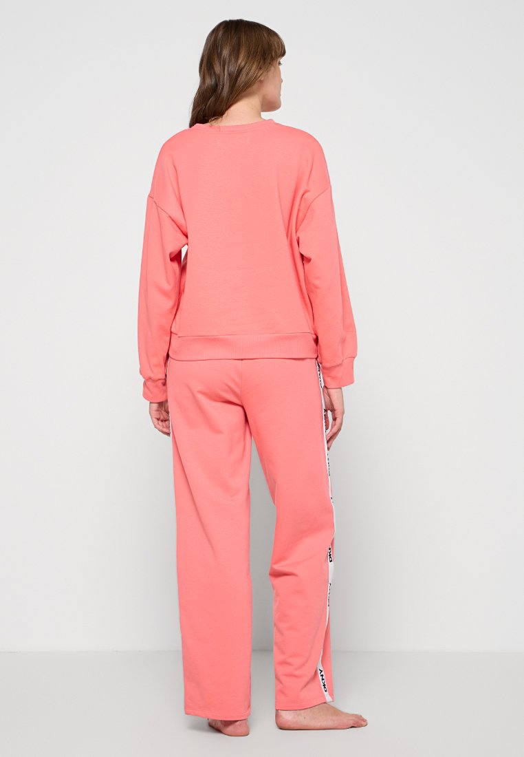 Korallenfarbene Sweatshirt- und Hosenkombination in lockerem Schnitt. Die Hosen haben seitliche Streifen und gerippte Bündchen. Aus einem weichen, strapazierfähigen Stoff gefertigt.