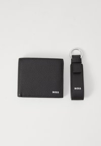 Black leather wallet with textured finish and white "BOSS" logo. Accompanied by a matching key ring with a looped strap and logo detail.