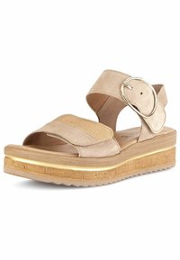 Sandali in suede beige con una chiusura in velcro e un accento metallico rotondo. Presentano una suola a piattaforma in legno con una finitura dorata e una superficie texture.