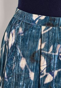 Gerimpelde rok met een blauw-wit abstract patroon, gemaakt van een gestructureerde stof en voorzien van een elastische tailleband voor een goede pasvorm.