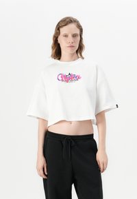 Tricou alb scurt, cu decolteu rotund și mâneci scurte, având un imprimeu grafic colorat cu inscripția „Alterra Studio Edition.”