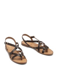 Brązowe skórzane sandały mają krzyżujące się paski, otwarty tył i płaską podeszwę. Wkładka ma gładkie, jasnobrązowe wykończenie. Dołączona klamra.