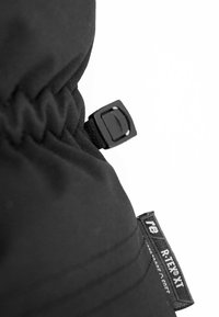 Nahaufnahme von schwarzem Stoff mit strukturierter Oberfläche, einem schwarzen Verschluss und einem kleinen Etikett mit "R.TEX® XT". Sichtbare Nahtdetails.