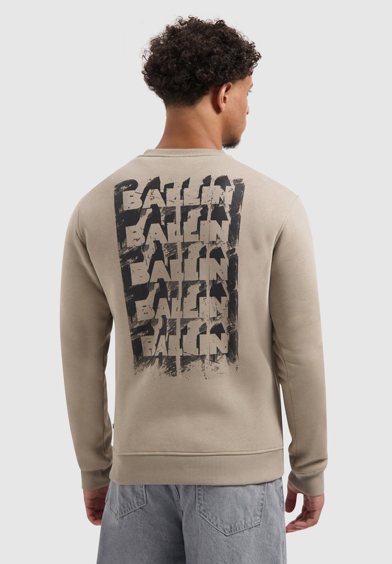 Beige sweatshirt met een gestructureerde, zwarte grafische print met het woord "BALLIN" herhaald op de achterkant. Ribgebreide boorden en halslijn.