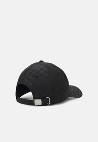 Black cap with a textured pattern, curved brim, adjustable strap at the back, and a silver metal buckle detail.