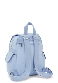 Mochila azul claro con correas ajustables, asa superior, bolsillo trasero con cremallera y dos bolsillos laterales con solapa sobre un fondo blanco.