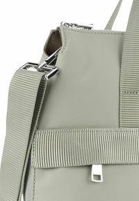 Szara syntetyczna torba na ramię z zamkiem błyskawicznym, szerokim paskiem z tkaniny i metalowymi akcentami. Posiada akcent w postaci żebrowanego paska oraz elegancki design.