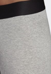 Harmaat legginsit, joissa on sileä ja pehmeä pinta sekä leveä musta vyötärönauha. Kangas on heather-mallia ilman näkyviä saumoja.
