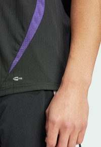 Zwart sportshirt met verticale strepen, voorzien van een paarse accent en een "CLIMACOOL" label op de onderrand. Lichtgewicht, ademend materiaal.