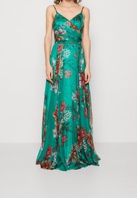 Long, teal dress with a floral pattern in red, pink, and white. Features a V-neck, thin straps, and a flowing skirt. Smooth texture.