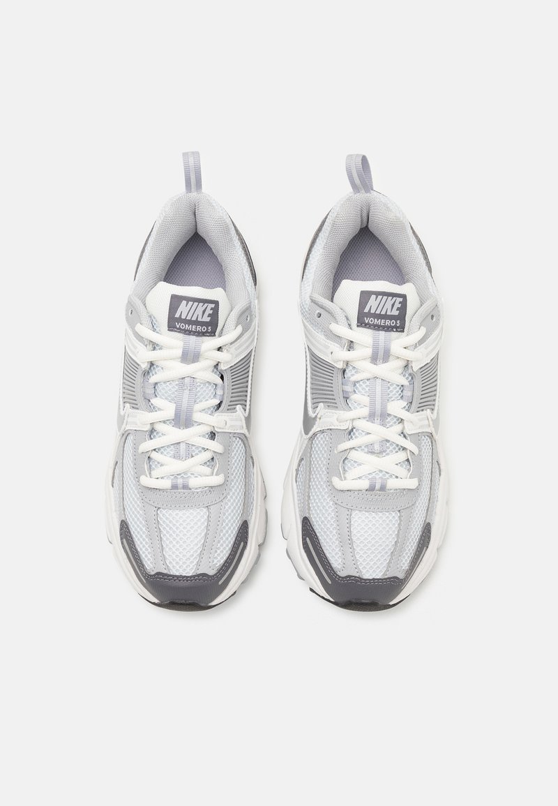 Nike Vomero 5 sneakers in grijs en wit. Bovenwerk van mesh met een gevoerde tong, veters en een stevige rubberen outsole. Rond ontwerp van de teen.